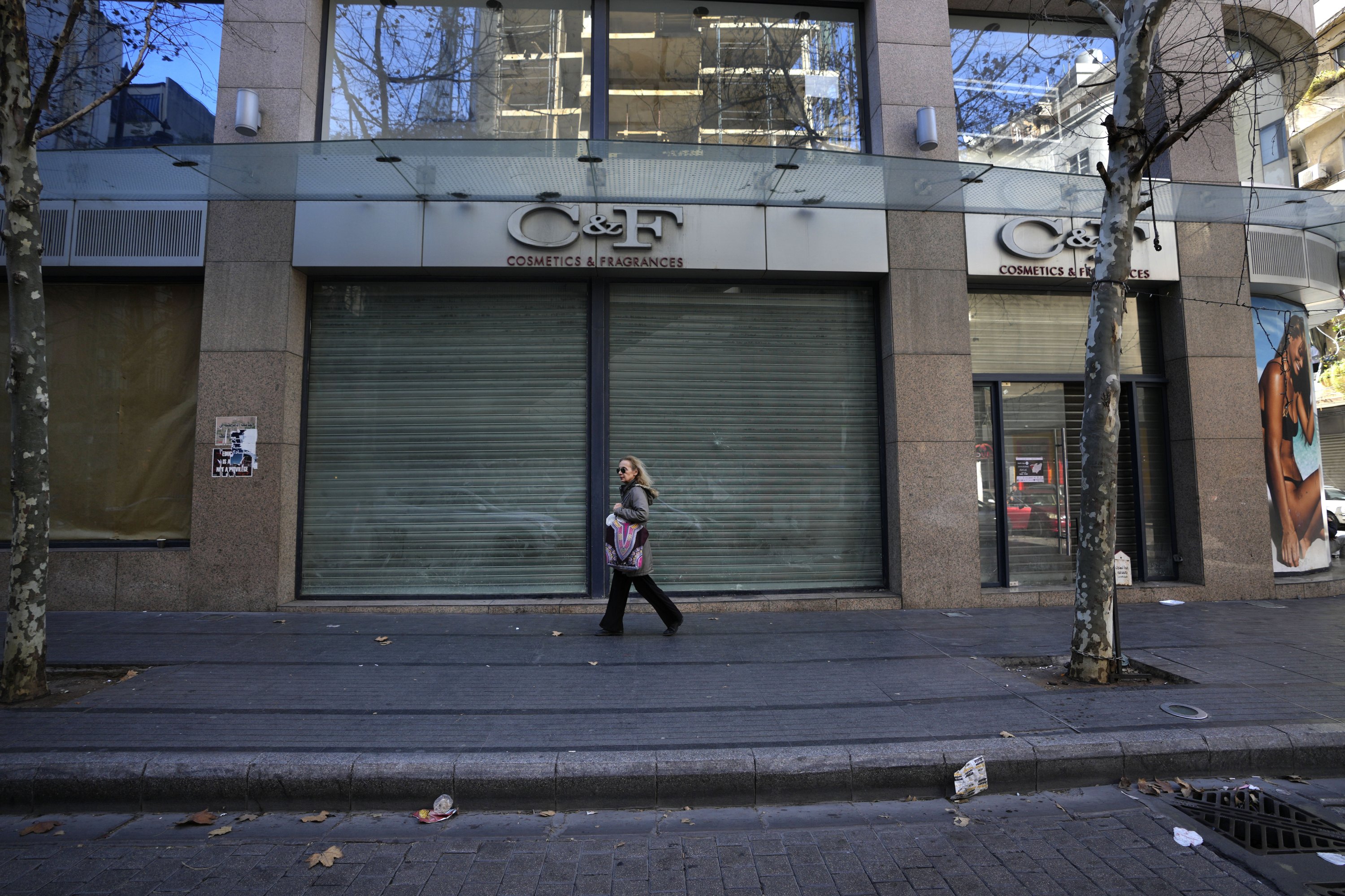 A woman passes next to one of the bigger cosmetic shops that closed forever after the economic crisis at the commercial Hamra Street, in Beirut, Lebanon, Jan. 12, 2022. (AP Photo)