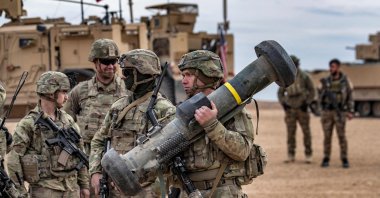 A U.S. soldier carries a javelin surface-to-air missile launcher during a joint military exercise between the PKK terrorist group and the U.S.-led international coalition against Daesh, in the countryside of Deir Ezzor in northeastern Syria, Dec. 7, 2021. (AFP Photo)
