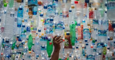 An Indonesian activist from ECOTON prepares an installation made with used plastic, including 4,444 bottles, collected from the river in Gresik, Indonesia, Sept. 17, 2021. (AFP Photo)