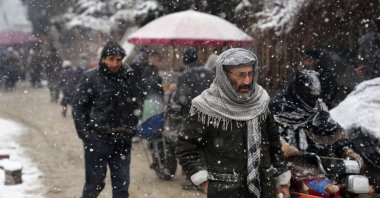 Afghan citizens walk under the sow at a popular market, in Kabul, Afghanistan, Feb. 6, 2022. (AP Photo)