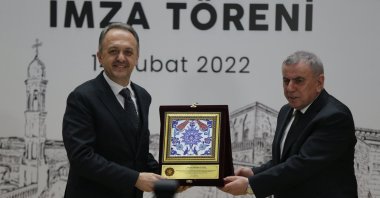 Midyat Mayor Veysi Şahin (R) gifts Cultural Heritage and Museums General Manager Gökhan Yazgı a plaque commemorating the signing of a protocol to work toward applying for a UNESCO World Heritage Temporary Listing of nine churches and monasteries, Mardin, southeastern Turkey, Feb. 14, 2022. (AA Photo)