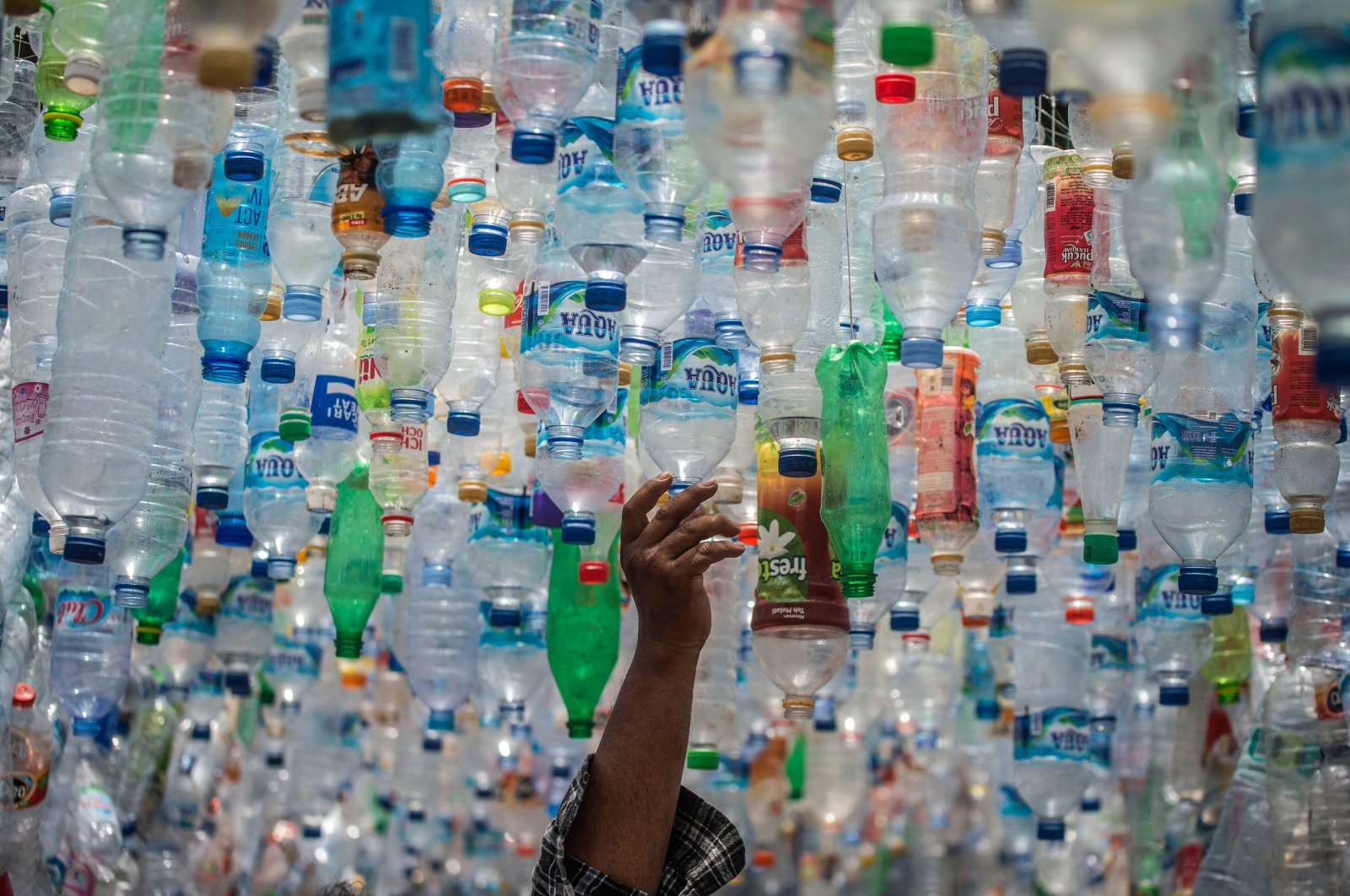 An Indonesian activist from ECOTON prepares an installation made with used plastic, including 4,444 bottles, collected from the river in Gresik, Indonesia, Sept. 17, 2021. (AFP Photo)