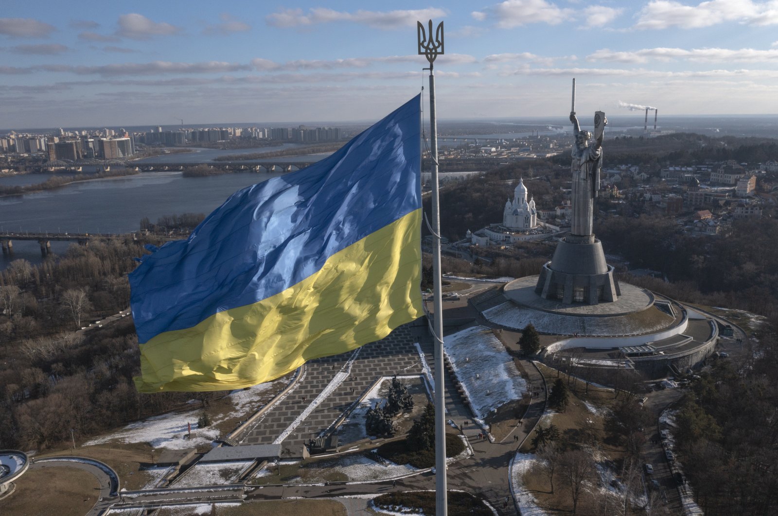 A view of Ukraine&#039;s national flag waves above the capital with the Motherland Monument on the right, in Kyiv, Ukraine, Feb. 13, 2022. (AP Photo)