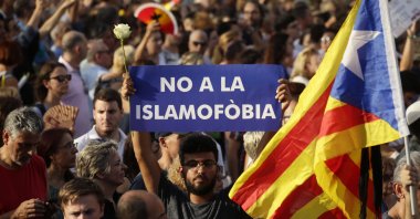 A young man holds a rose and a sign reading in Spanish "No to Islamophobia" in Barcelona's Plaza Catalonia during a demonstration condemning the attacks that killed 15 people in Barcelona, Spain, Aug. 26, 2017. (AP File Photo)