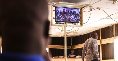 Patrons watch the inauguration ceremony of Lt. Col. Paul-Henri Sadaogo Damiba as Burkina Faso president on a television set from a coffee shop, Ouagadougou, Burkina Faso, Feb. 16, 2022. (AFP Photo)