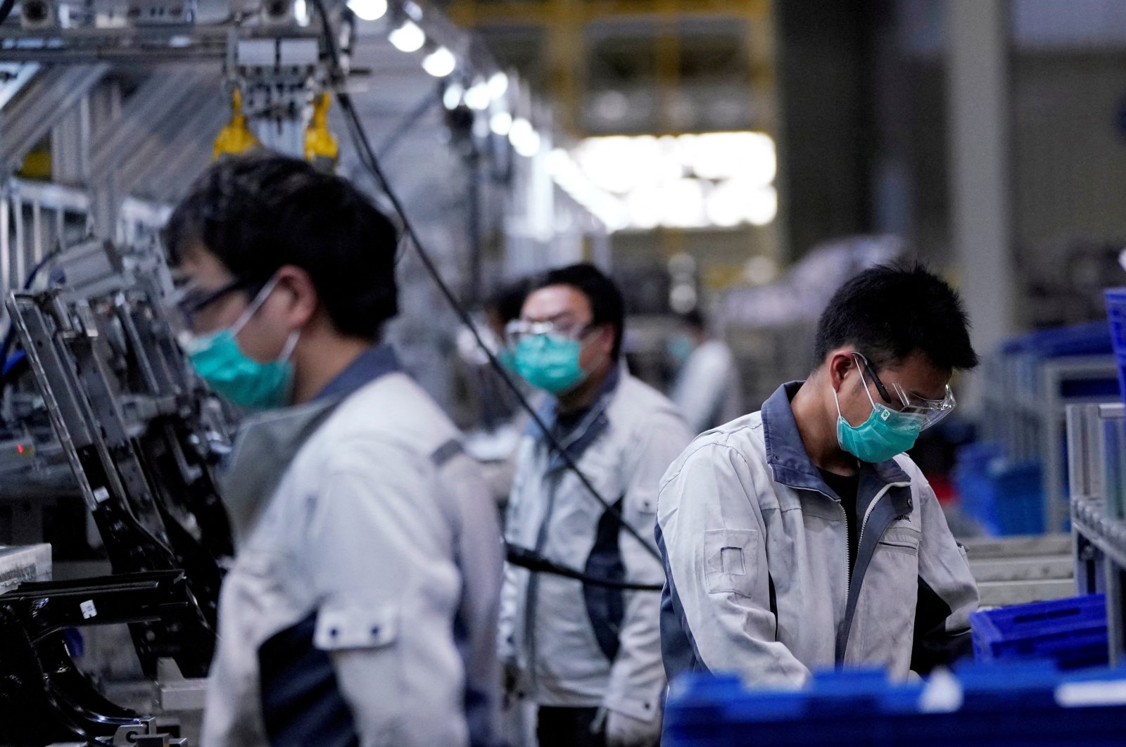 Employees wearing face masks work on a car seat assembly line at Yanfeng Adient factory in Shanghai, China, Feb. 24, 2020. 