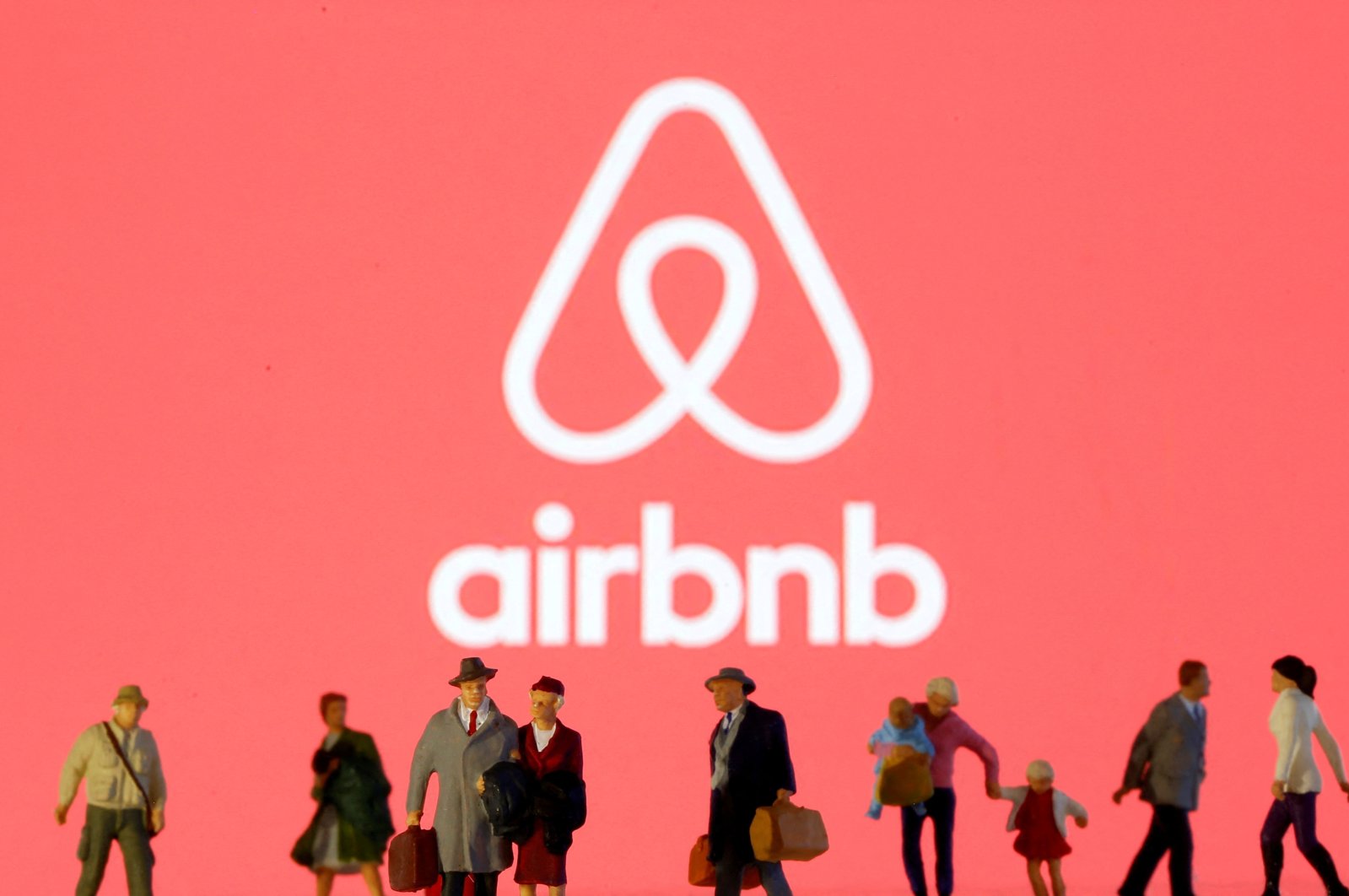 An Airbnb logo is displayed with small toy figures, March 19, 2020. (Reuters Photo)