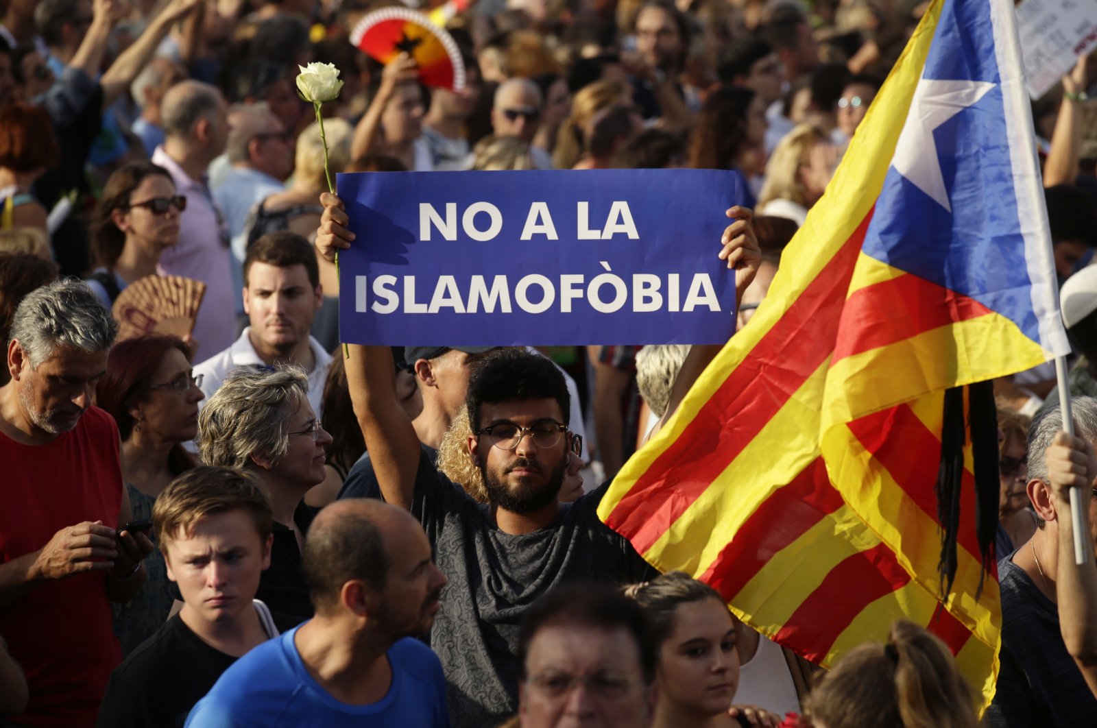 A young man holds a rose and a sign reading in Spanish "No to Islamophobia" in Barcelona&#039;s Plaza Catalonia during a demonstration condemning the attacks that killed 15 people in Barcelona, Spain, Aug. 26, 2017. (AP File Photo)