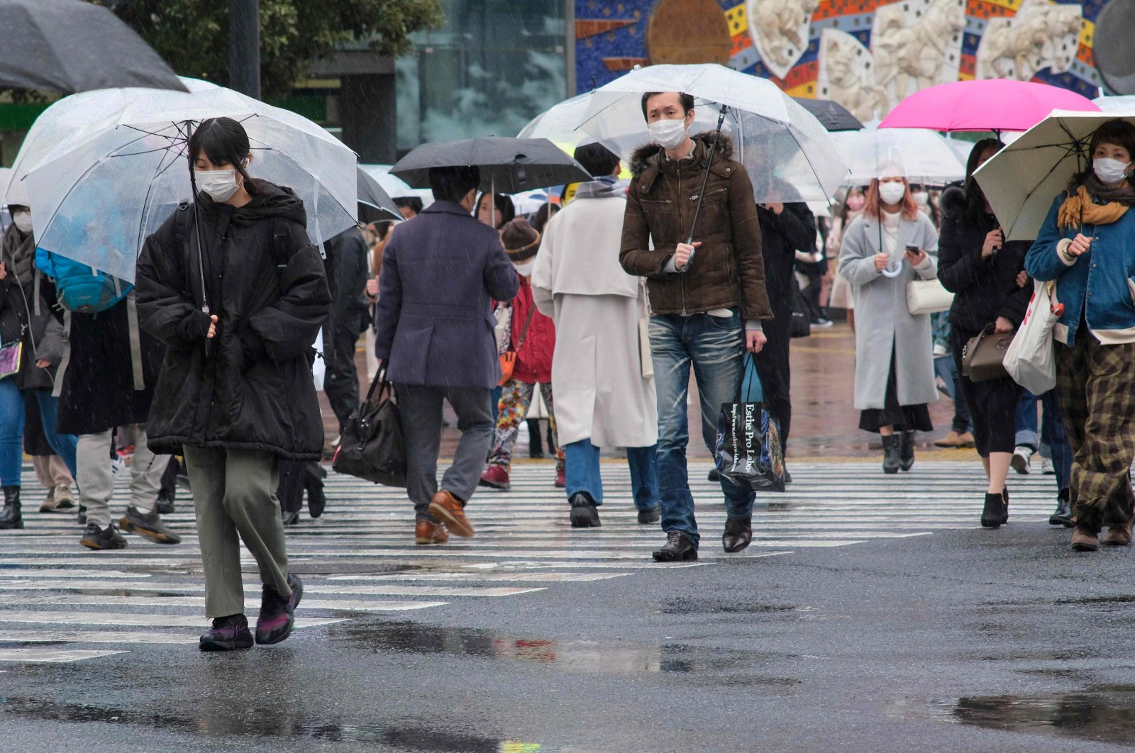 People walk at Shibuya crossing in rainy Tokyo, Japan, Feb. 13, 2022, amid the coronavirus pandemic. (AFP Photo)