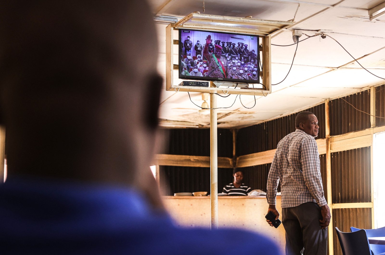 Patrons watch the inauguration ceremony of Lt. Col. Paul-Henri Sadaogo Damiba as Burkina Faso president on a television set from a coffee shop, Ouagadougou, Burkina Faso, Feb. 16, 2022. (AFP Photo)