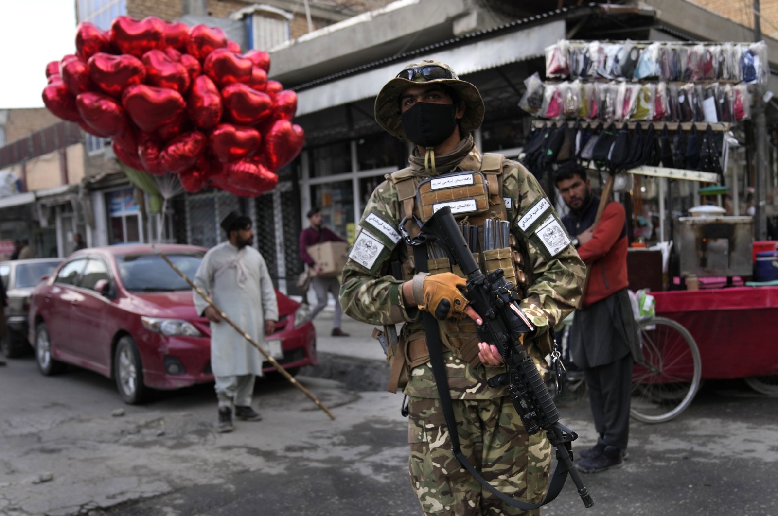 A Taliban fighter passes in front of a street vendor selling red heart-shaped balloons for Valentine&#039;s Day in Kabul, Afghanistan, Feb. 14, 2022. (AP Photo)