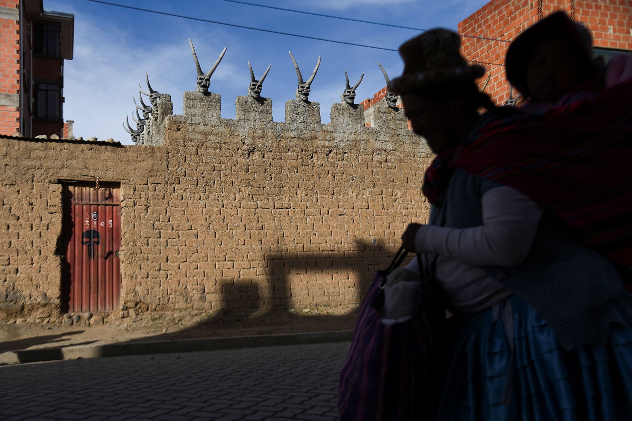 A woman walks past the house of Bolivian miner David Choque who has covered his house with sculptures of horned devils, in El Alto, Bolivia, Feb. 16, 2022. (Reuters Photo)