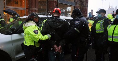 Police officers escort an arrested protester to a police car during a protest over pandemic health rules and the Trudeau government in Ottawa, Canada, Feb. 17, 2022. (AFP Photo)