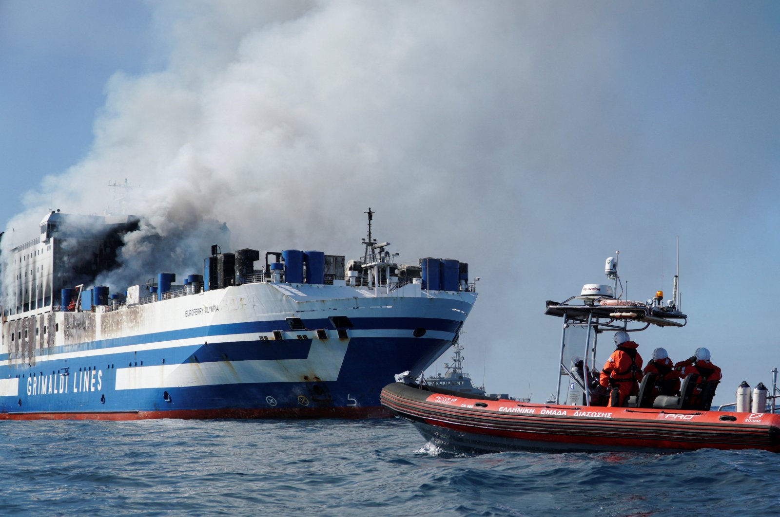 Rescuers watch as smoke rises from the burning Italian-flagged Euroferry Olympia, after a fire broke out on the ferry, off the island of Corfu, Greece, Feb. 18, 2022. (REUTERS Photo)