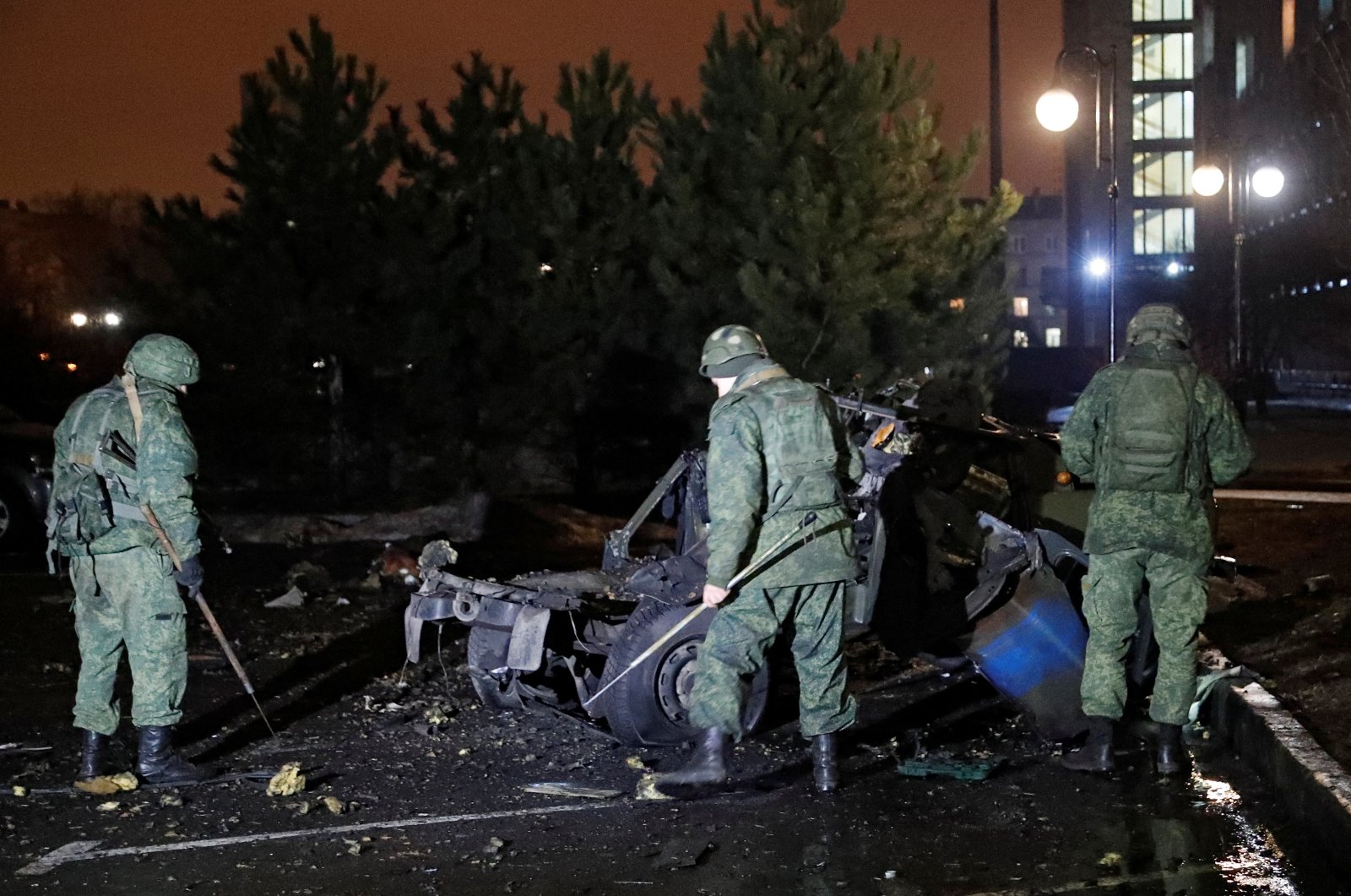 Specialists inspect the wreckage of a car that, according to the local authorities, was blown up near the government building, in the rebel-controlled city of Donetsk, Ukraine, Feb. 18, 2022. (Reuters Photo)