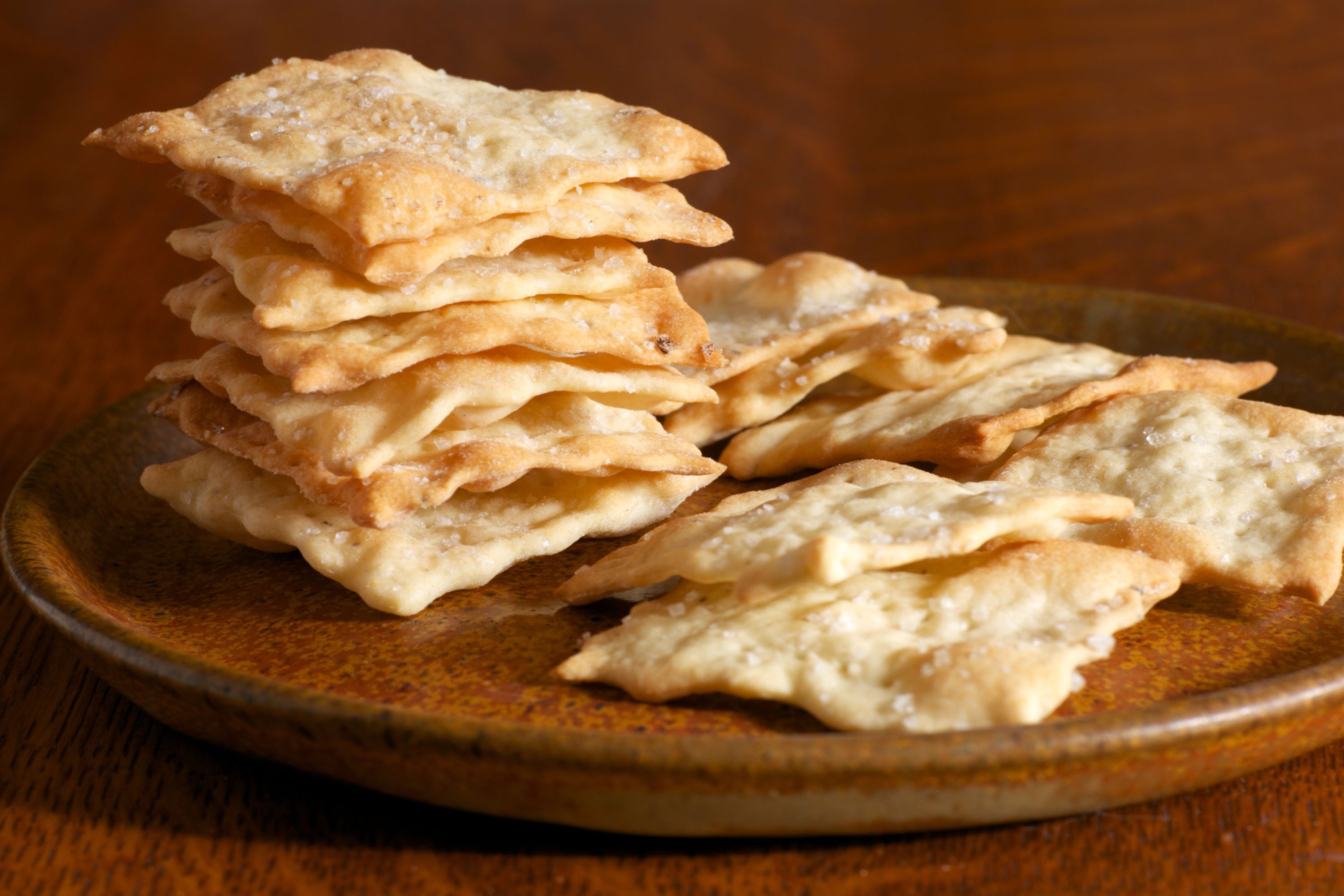 Homemade plain crackers with sea salt and cracked pepper on a plate. (Shutterstock) 