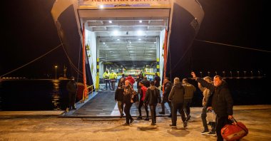 Turkish nationals wave as they board a ferry on their way to Turkey on the Greek Ionian island of Corfu on Feb. 19, 2022, after being rescued from the Italian-flagged Euroferry Olympia that caught fire earlier. (AFP Photo)