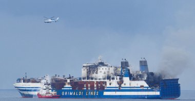 A Greek Navy helicopter flies over the burning Italian-flagged Euroferry Olympia, which sailed from Greece to Italy early on Friday and caught fire, off the coast of the island of Corfu, Greece, Feb. 20, 2022. (Reuters Photo)
