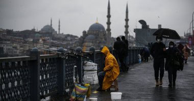 People wearing masks walk over Galata Bridge in Istanbul during the COVID-19 pandemic, Turkey, Feb. 3, 2022. (AP File Photo)