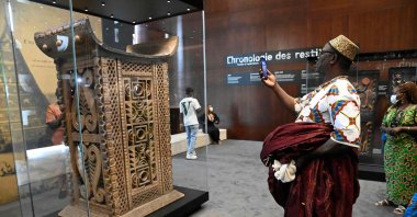A man in traditional wares photographs with his smartphone the ceremonial throne of King Ghezo, one of the artifacts looted by French colonial soldiers returned and displayed for viewing by the general public during an exhibition at the presidency in the capital Cotonou, Benin, on Feb. 20, 2022. (Photo by PIUS UTOMI EKPEI / AFP)