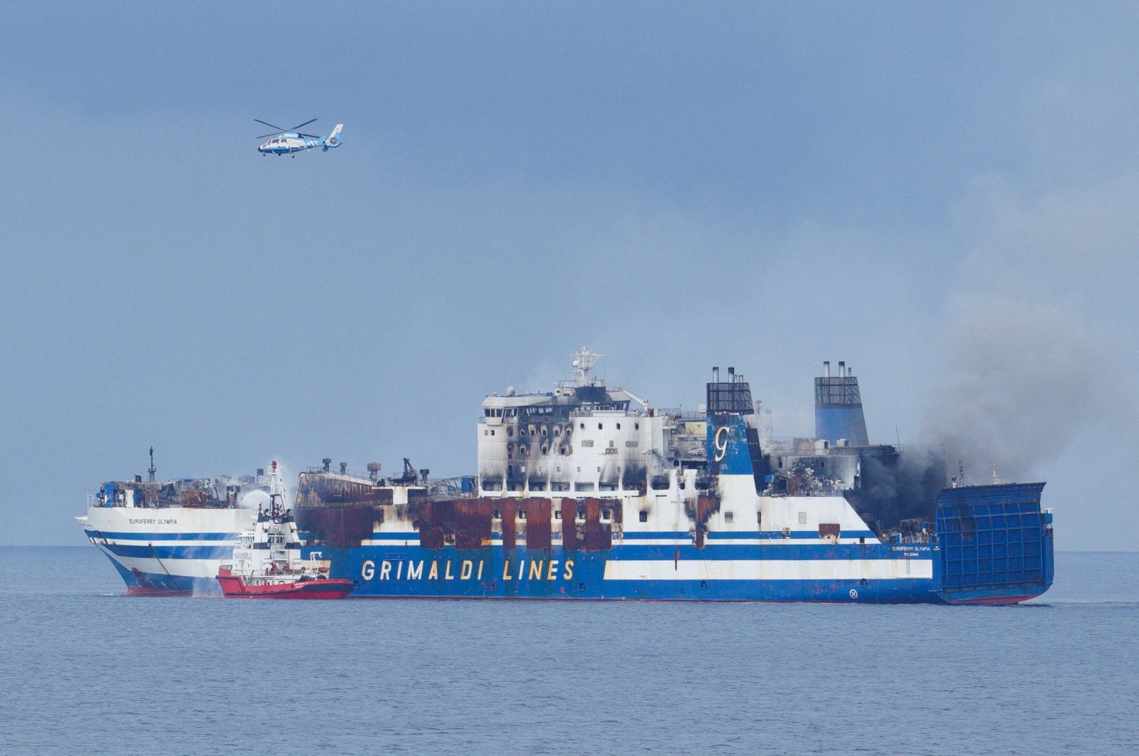 A Greek Navy helicopter flies over the burning Italian-flagged Euroferry Olympia, which sailed from Greece to Italy early on Friday and caught fire, off the coast of the island of Corfu, Greece, Feb. 20, 2022. (Reuters Photo)