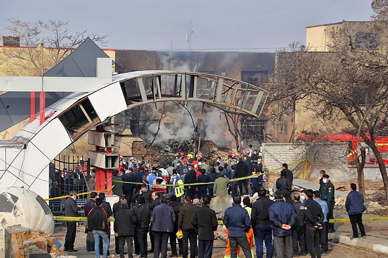 A handout picture provided by the news agency Tasnim on February 21, 2022 shows residents gathering at the crash site of a fighter jet in a residential area of the northwestern city of Tabriz.(Tasnim News Agency via AFP)