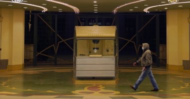A man walks underneath the marquee of the Alex Theatre, which bears a message urging people to get COVID-19 vaccine booster shots, Glendale, California, U.S., Jan. 24, 2022. (AP Photo)