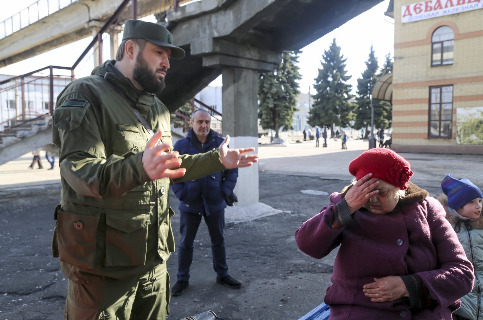 An elderly woman reacts to a soldier as she arrives to board a train to be evacuated to Russia, at the railway station in Debaltseve, the territory controlled by pro-Russian militants, eastern Ukraine, Feb. 19, 2022. (AP Photo)