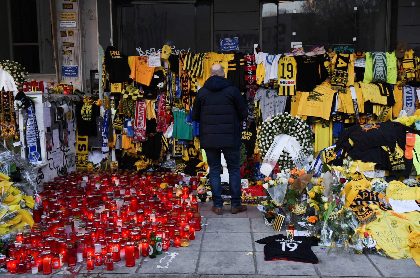 A man stands at the site, where a 19-year-old fan of Aris Thessaloniki, Alkis Kampanos, was fatally stabbed, Thessaloniki, Greece, Feb. 7, 2022. (Reuters Photo)