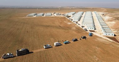 This picture shows an aerial view of internally displaced Syrians arriving with their belongings in a convoy of trucks, at a new housing site in the opposition-held area of Bizaah, east of the city of al-Bab in the northern Aleppo governorate, built with the support of Turkey's emergencies agency AFAD, after leaving a nearby camp, Bizaah, Syria, Feb. 9, 2022. (AFP Photo)