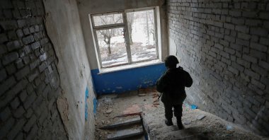 A militant of the self-proclaimed Luhansk People&#039;s Republic patrols the damaged building of a local school located near the line of separation from Ukrainian forces in the settlement of Molodizhne (Molodezhnoye), Luhansk region, Ukraine, Feb. 17, 2022. (Reuters Photo)