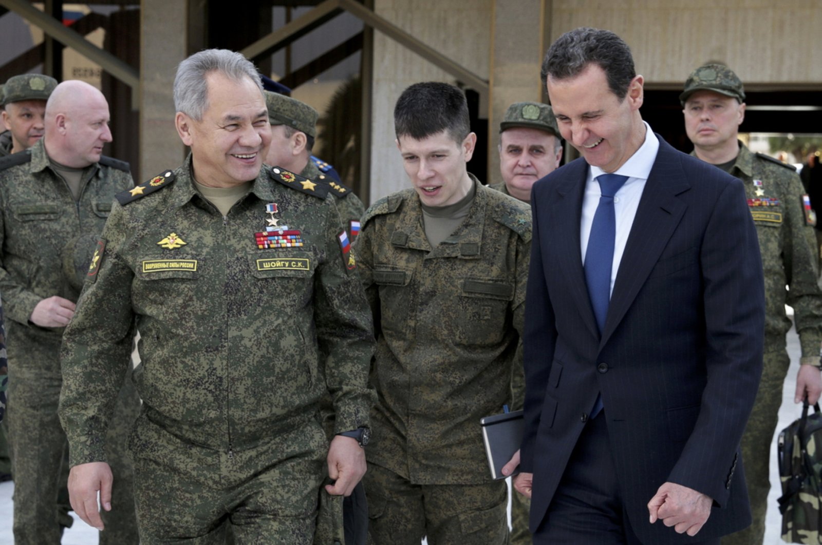 In this photo taken from video provided by the Russian Defense Ministry Press Service, Feb. 15, 2022, Russian Defense Minister Sergei Shoigu (L) and Syrian Bashar Assad (R) smile during their meeting in Damascus, Syria. (AP Photo)