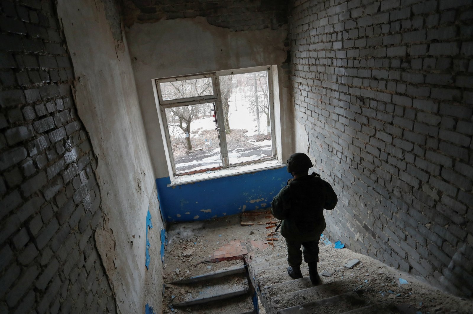 A militant of the self-proclaimed Luhansk People&#039;s Republic patrols the damaged building of a local school located near the line of separation from Ukrainian forces in the settlement of Molodizhne (Molodezhnoye), Luhansk region, Ukraine, Feb. 17, 2022. (Reuters Photo)