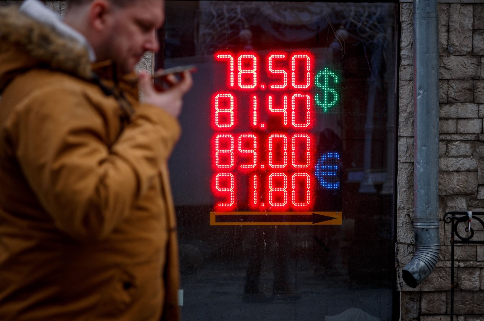 A man walks past a board showing currency exchange rates of the U.S. dollar and the euro against the Russian ruble in Moscow, Russia, Feb. 22, 2022. (AFP Photo)