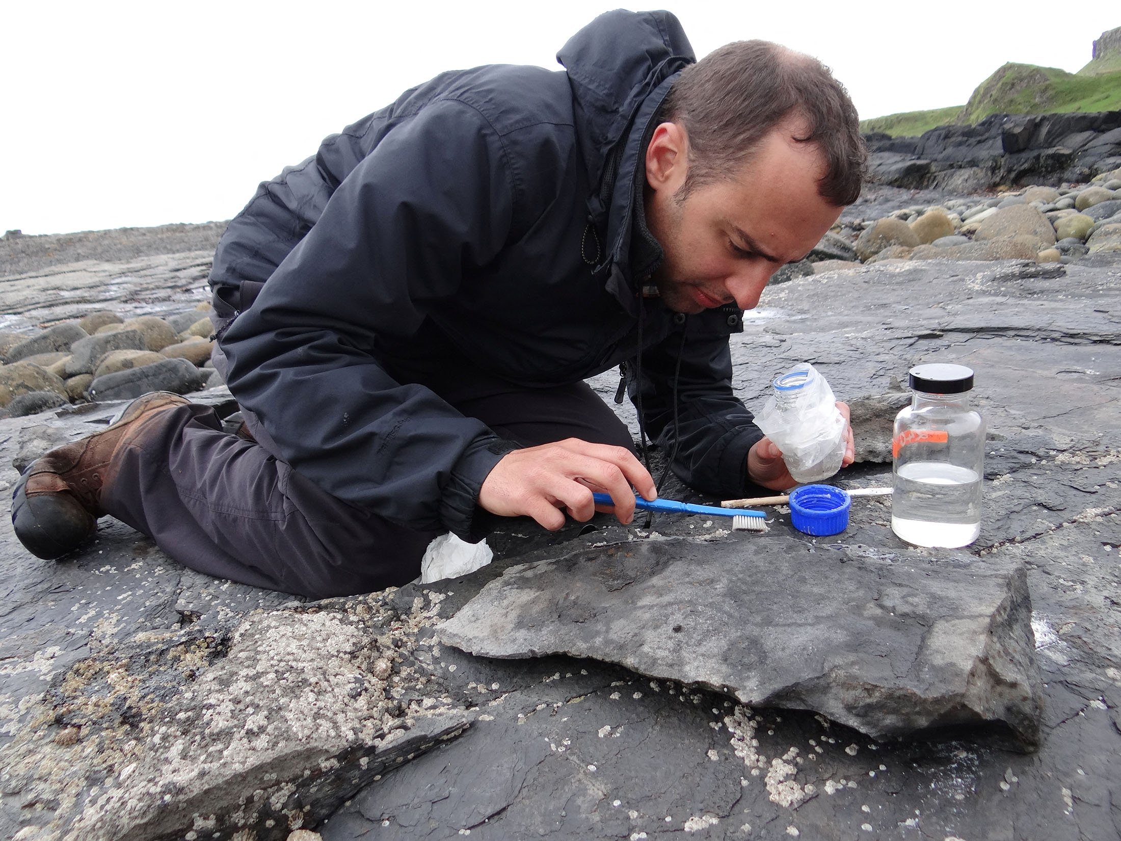 University of Edinburgh paleontologist Steve Brusatte works to conserve part of the fossil of a newly identified Jurassic Period flying reptile, or pterosaur, called "Dearc sgiathanach," found on a rocky beach at Scotland's Isle of Skye, U.K., May, 2017. (Shasta Marrero via Reuters)