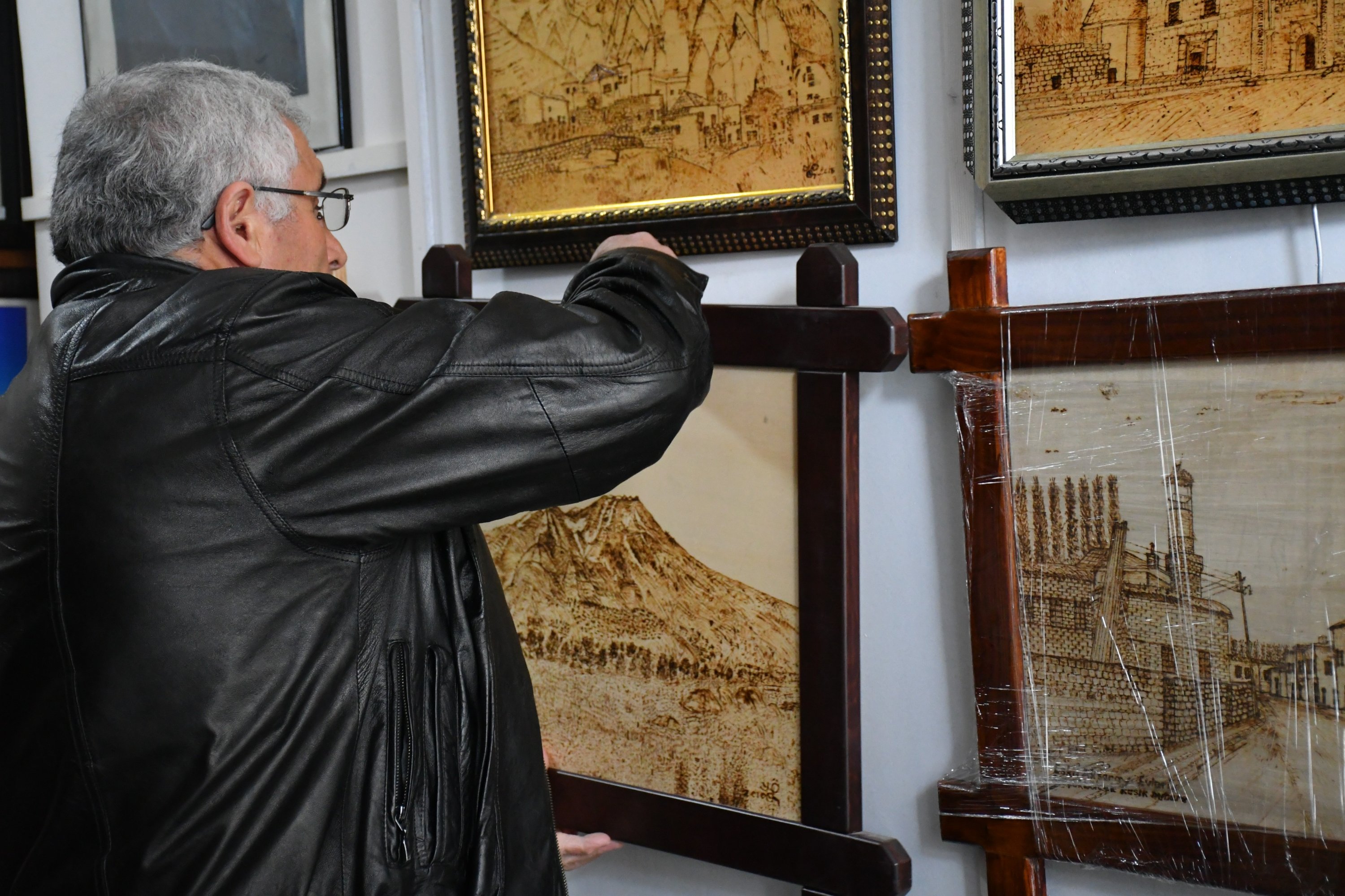 Self-taught woodcarver Yılmaz Öngün hanging up a framed etching in his workshop, Aksaray, central Turkey, Feb. 20, 2022. (IHA Photo)
