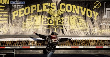 A supporter poses under a truck-mounted banner reading "People&#039;s Convoy" during the gathering ahead of its departure, at the Adelanto Stadium, Adelanto, California, U.S., Feb. 22, 2022. (EPA Photo)