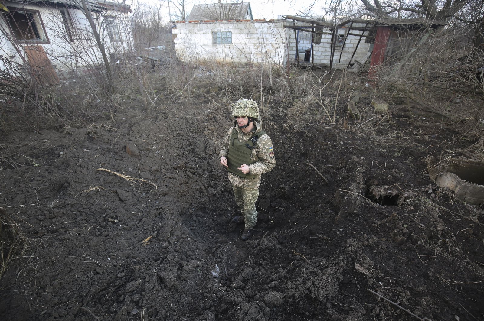 A Ukrainian officer shows a shell hole after shelling in the Zaytseve village not far from the pro-Russian militant-controlled city of Gorlivka Donetsk area, Ukraine, Feb. 21, 2022. (EPA File Photo)
