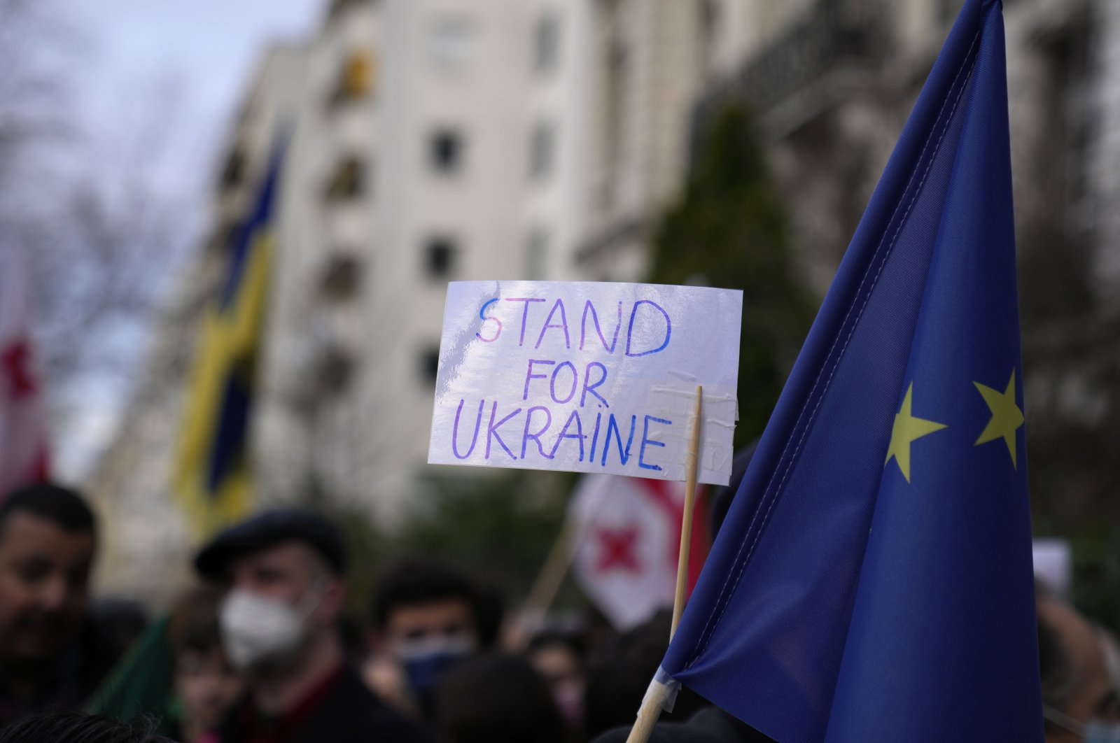 A protestor holds up a sign next to a European Union flag during a demonstration in front of the Russian Embassy in Paris, France, Feb. 22, 2022. (AP Photo)