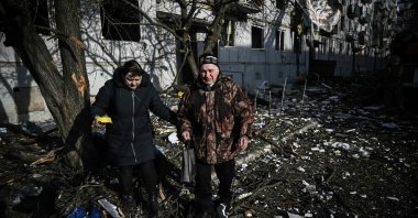People walk outside a destroyed building after bombings on the eastern Ukraine town of Chuguiv, Feb. 24, 2022. (AFP Photo)