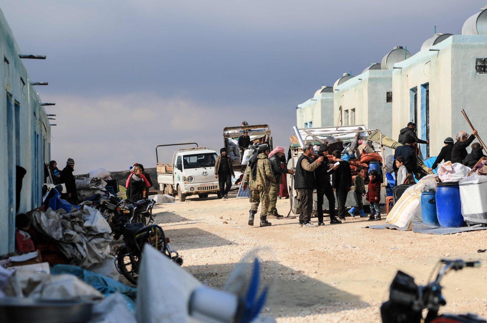 Internally displaced Syrians unload their belongings from trucks upon arrival at a new housing complex built with the support of Turkey&#039;s emergencies agency AFAD, in the opposition-held area of Bizaah, east of the city of al-Bab in the northern Aleppo governorate, Syria, on Feb. 9, 2022 (AFP Photo)