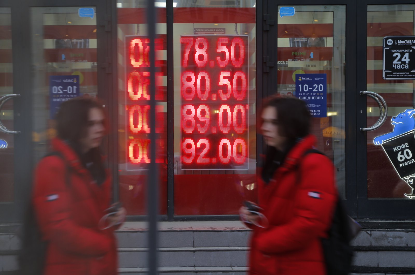 A woman walks near an exchange office screen showing the currency exchange rates of the U.S. dollar and the euro to Russian rubles, Moscow, Russia, Feb. 22, 2022. (AP Photo)