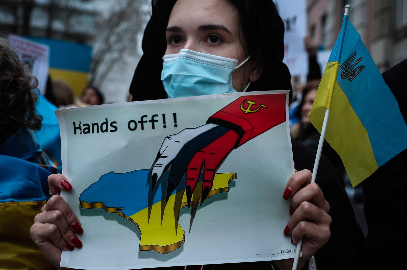 A demonstrator holds a sign depicting Ukraine and reading "Hands off!" during a protest against Russia&#039;s military operation of Ukraine, in front of the Russian embassy in Lisbon, Portugal, on Feb. 24, 2022. (AFP Photo)