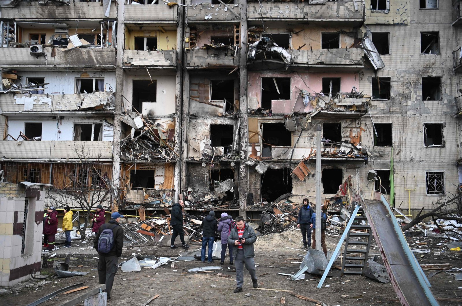 People gather in front of a damaged residential building on Koshytsa Street in a suburb of Kyiv, Ukraine, Feb. 25, 2022. (AFP Photo)