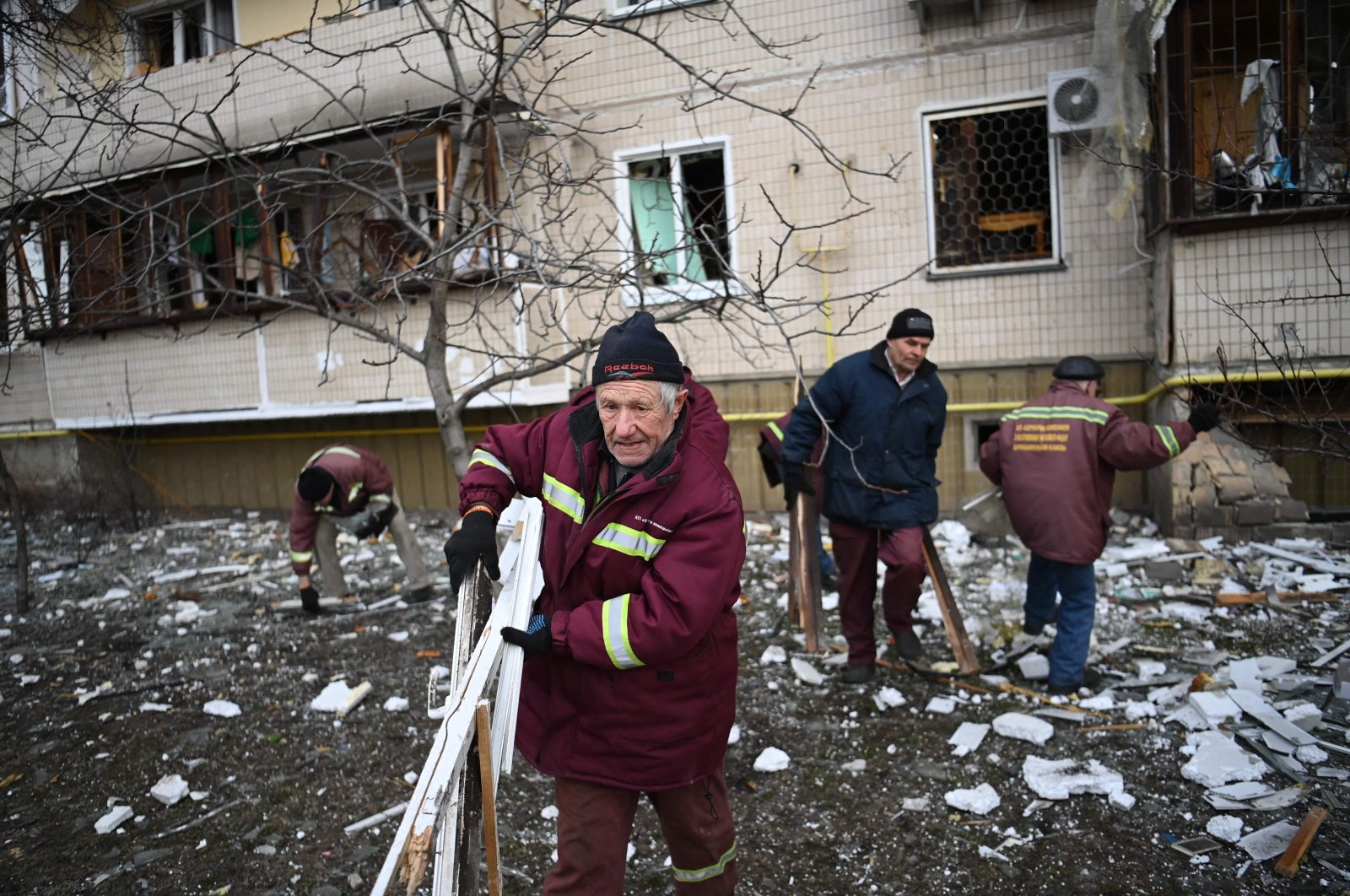 Men clear debris at a damaged residential building at Koshytsa Street, a suburb of the Ukrainian capital Kyiv, where a military shell allegedly hit, Feb. 25, 2022. (AFP Photo)