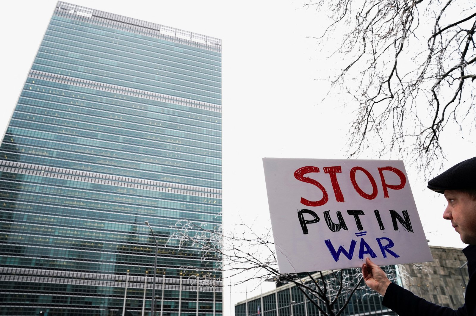 A lone protester stands with a sign condemning Vladimir Putin across the street from U.N. headquarters in Manhattan New York City, New York, U.S., Feb. 25, 2022.  (Reuters Photo)