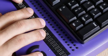 A visually impaired person using a computer with a braille keyboard is shown in this undated photo. (Shutterstock Photo)