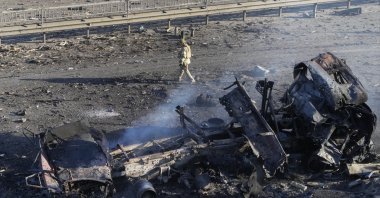 A Ukrainian soldier walks past the debris of a burning military truck, on a street in Kyiv, Ukraine, Feb. 26, 2022. (AP Photo)