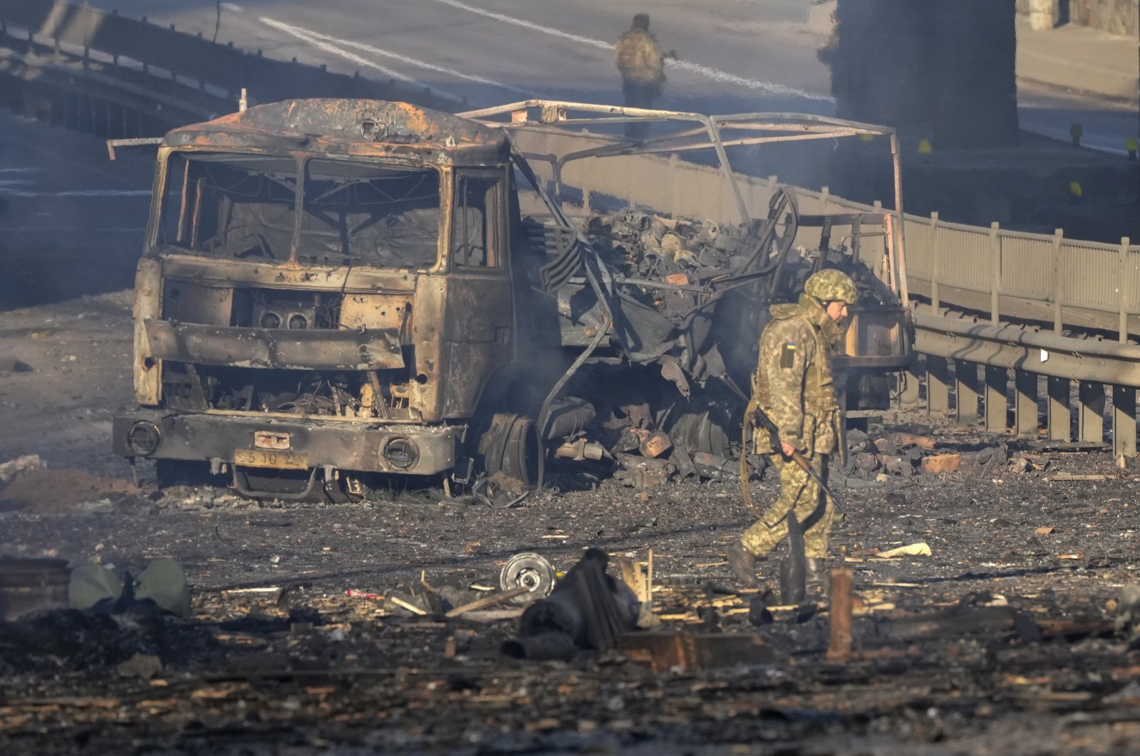 A Ukrainian soldier walks past debris of a burning military truck, on a street in Kyiv, Ukraine, Feb. 26, 2022. (AP Photo)