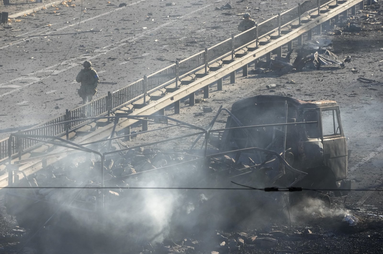 Ukrainian soldiers walk past the debris of a burning military truck, on a street in Kyiv, Ukraine, Feb. 26, 2022. (AP Photo)